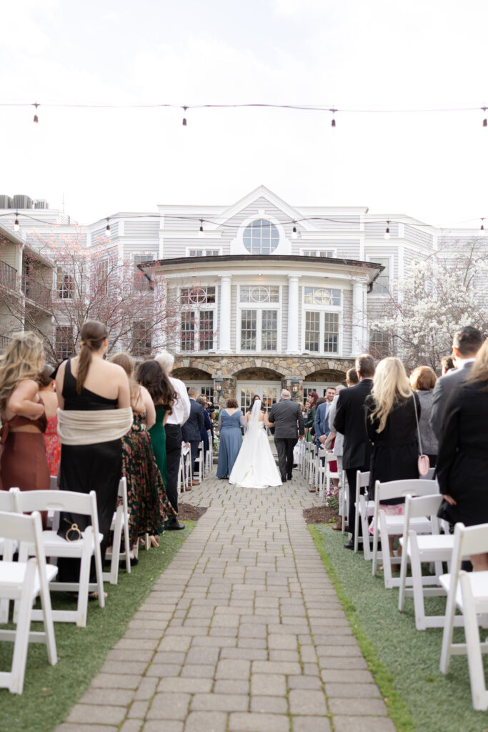 Bride and parents walking down the aisle during outdoor wedding ceremony