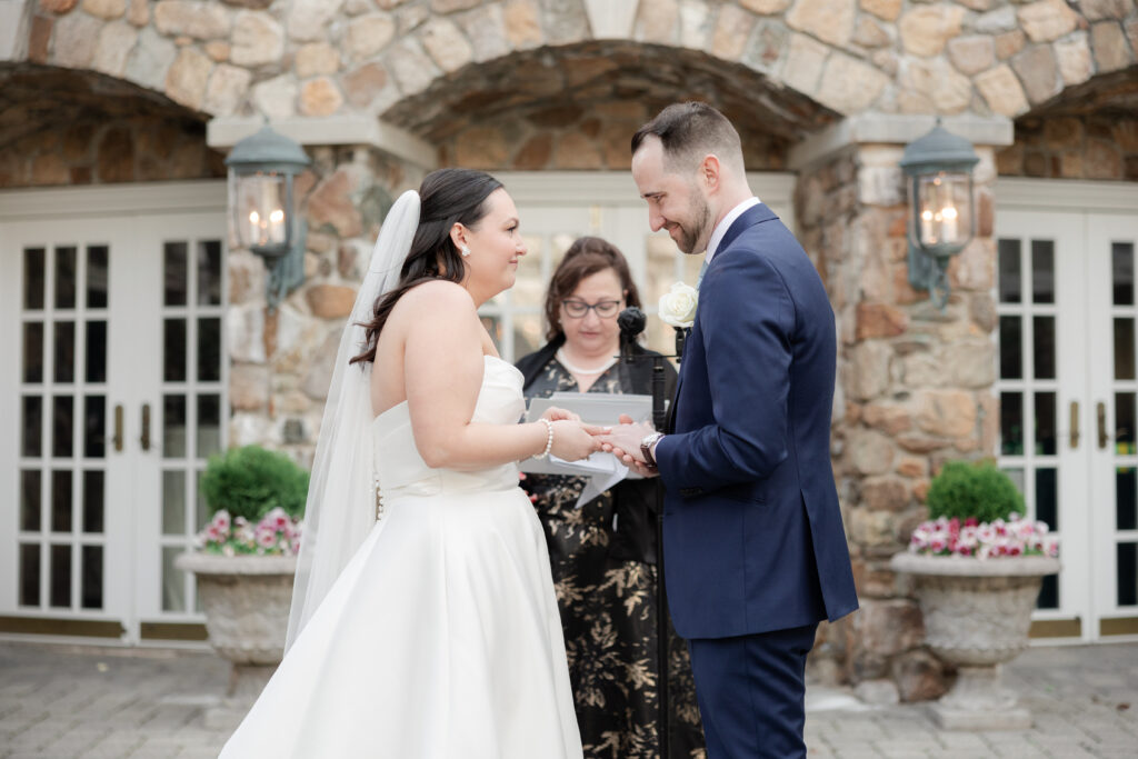 Bride and groom exchanging rings at outdoor wedding ceremony