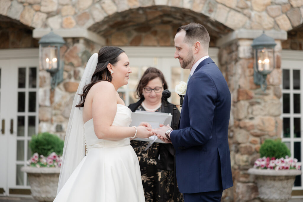 Bride and groom exchanging rings at outdoor wedding ceremony