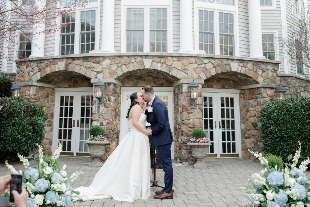 Bride and groom first kiss as husband and wife at outdoor wedding ceremony