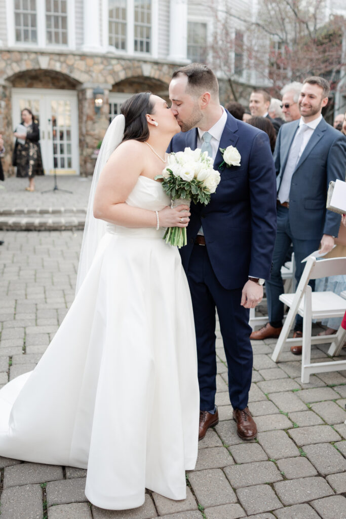 Bride and groom aisle kiss at outdoor wedding ceremony