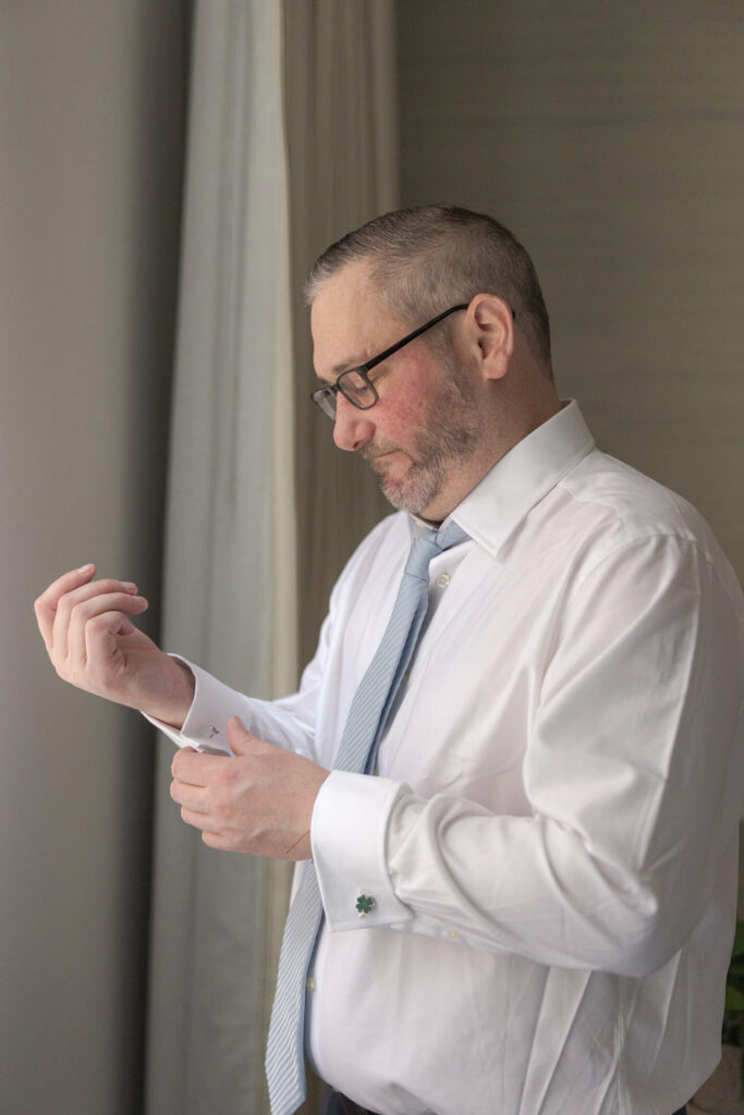 Groom in Wall Street Hotel's suite fixing cufflinks