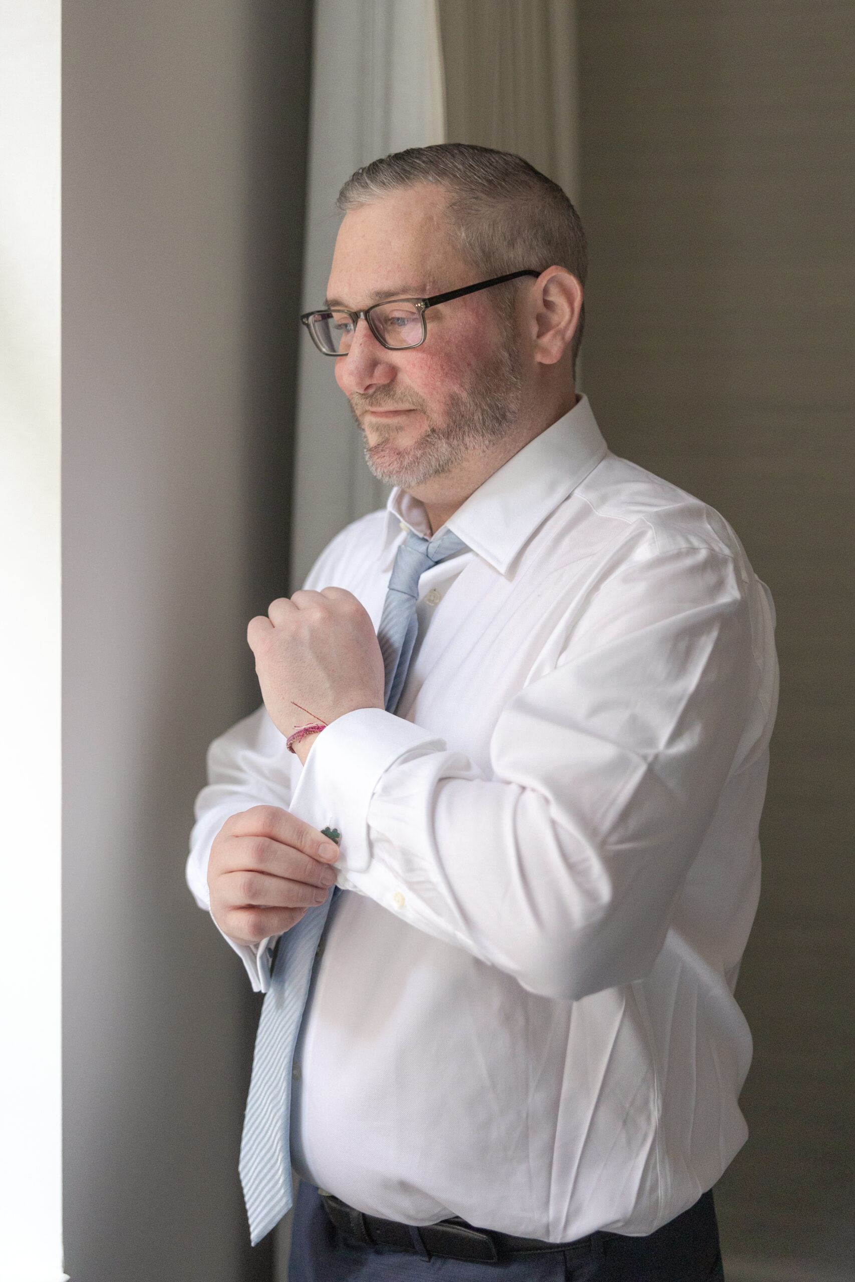 Groom in Wall Street Hotel's suite fixing cufflinks
