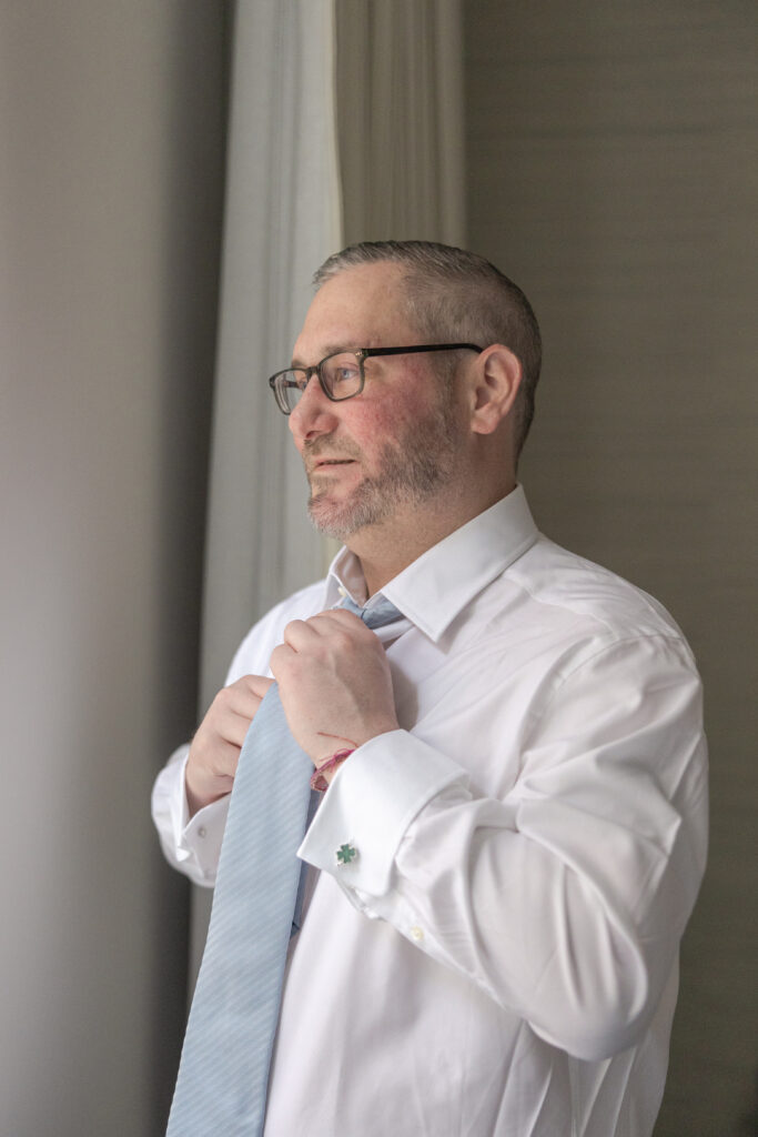 Groom in groomsmen suite fixing tie