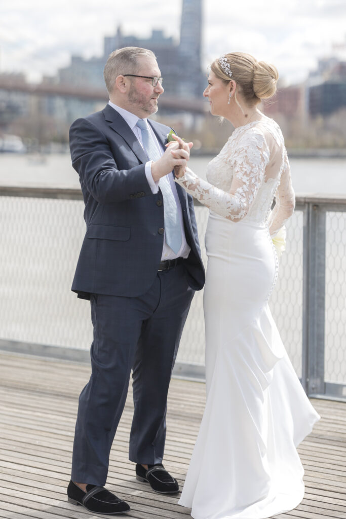 Bride and groom slow dancing in front of Brooklyn Bridge at Pier 16