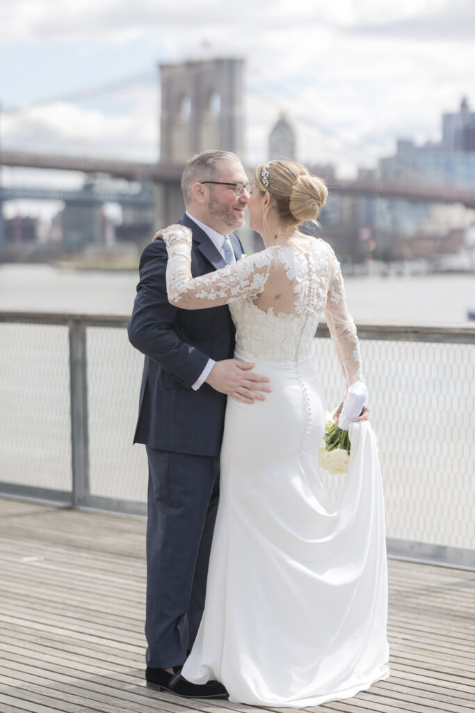 Bride and groom slow dancing in front of Brooklyn Bridge at Pier 16