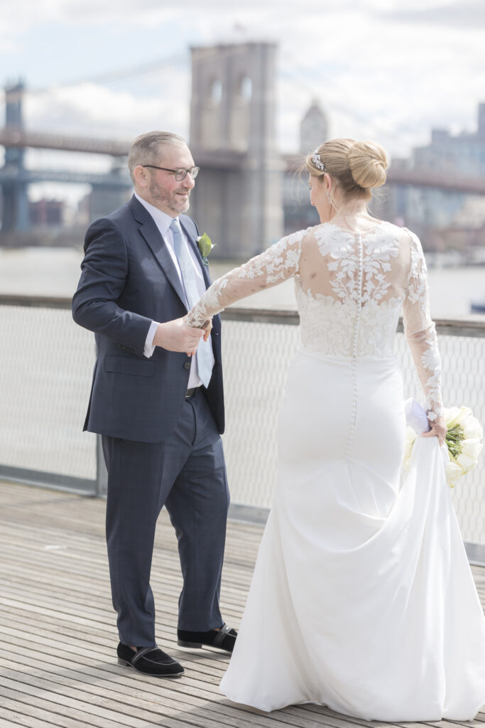 Bride and groom slow dancing in front of Brooklyn Bridge at Pier 16