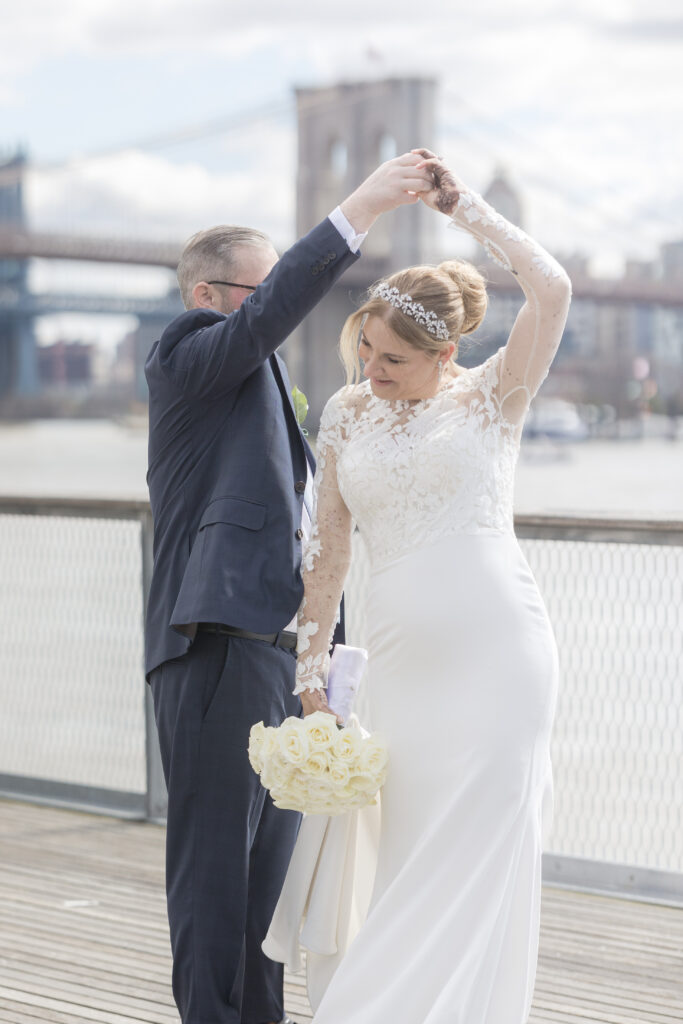 Bride and groom slow dancing in front of Brooklyn Bridge at Pier 16