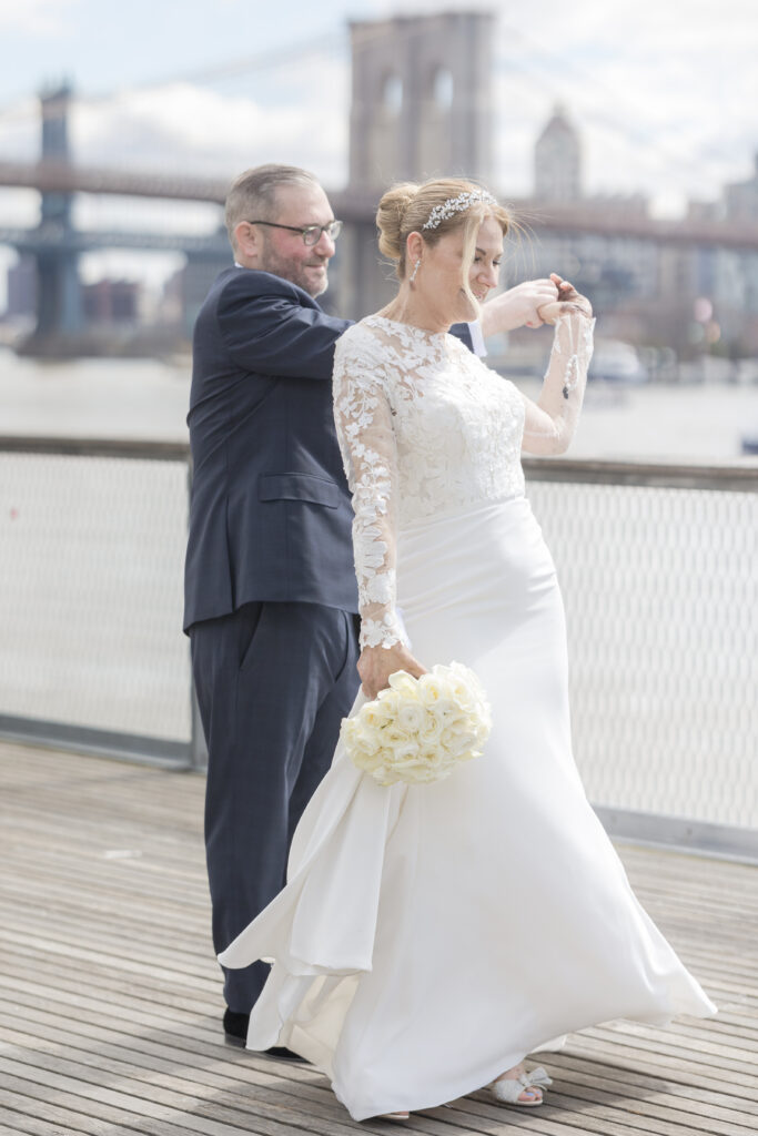 Bride and groom slow dancing in front of Brooklyn Bridge at Pier 16