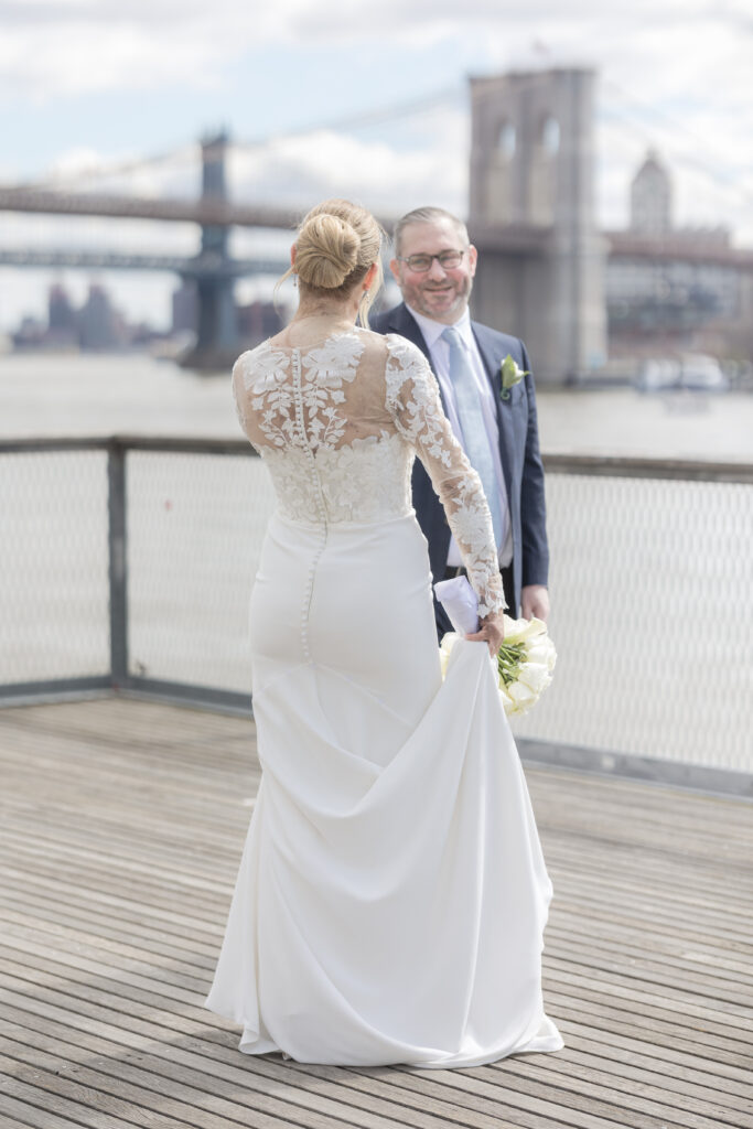 Bride and groom slow dancing in front of Brooklyn Bridge at Pier 16