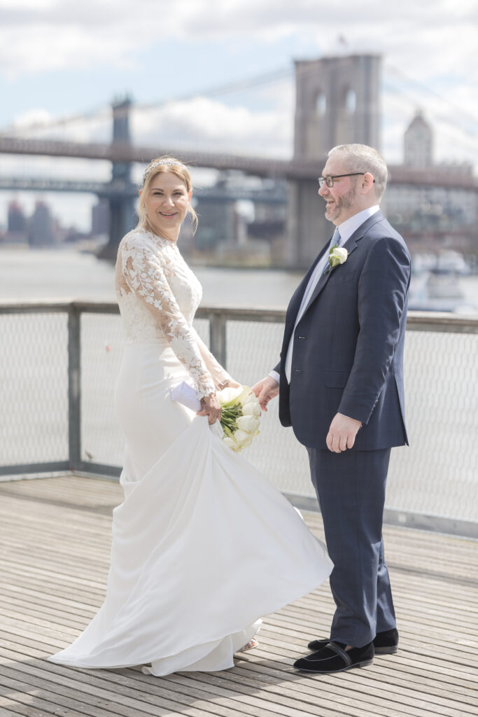 Bride and groom slow dancing in front of Brooklyn Bridge at Pier 16