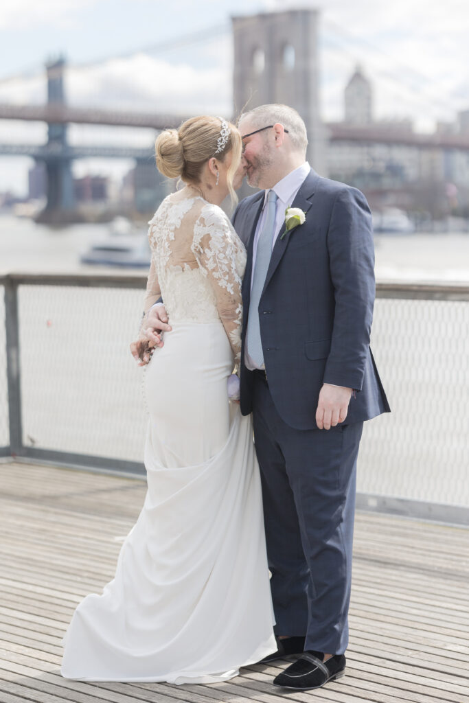 Bride and groom slow dancing in front of Brooklyn Bridge at Pier 16