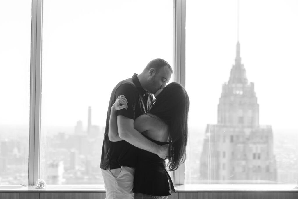 Black and white photo of engaged couple in front of skyline views