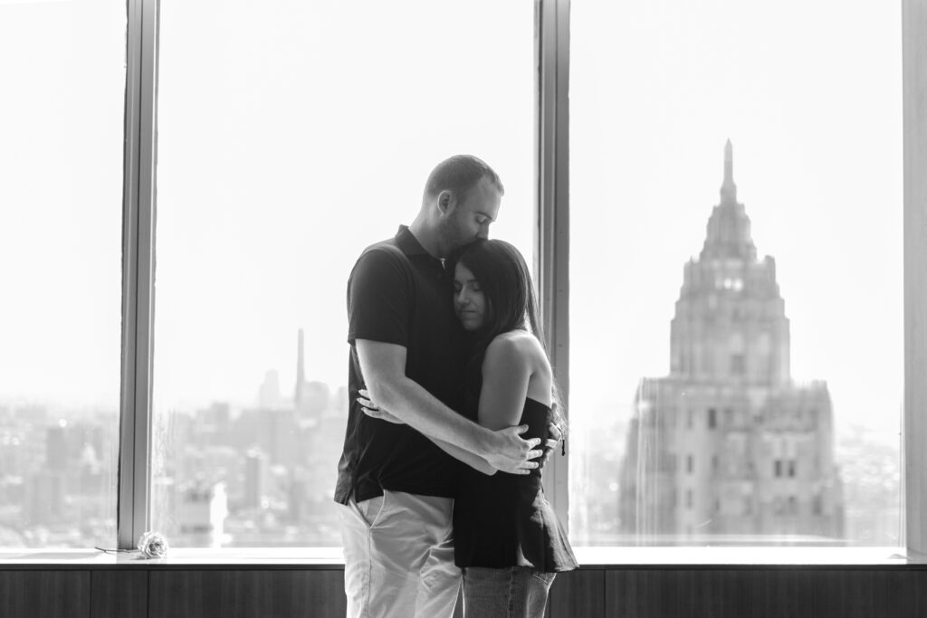 Black and white photo of engaged couple in front of skyline views