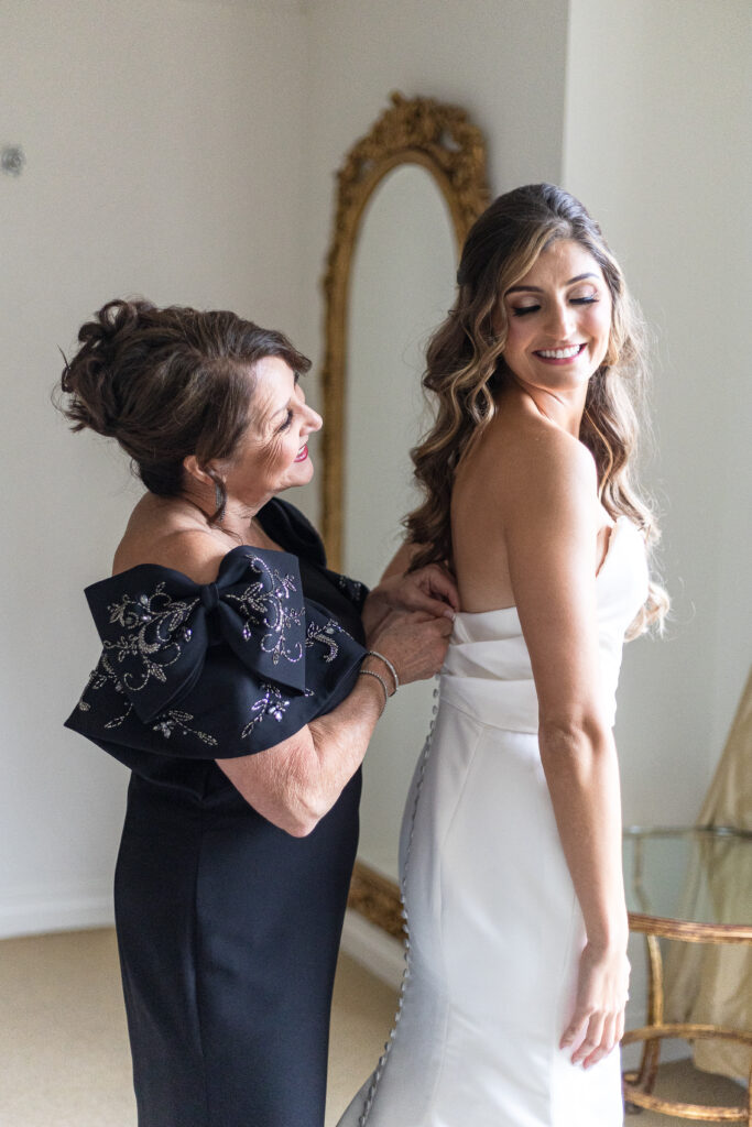Bride and mother of bride putting wedding dress on