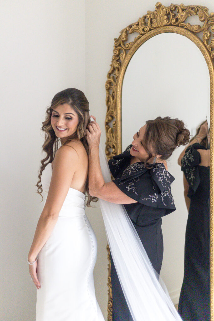 Bride and mother of bride putting wedding dress on