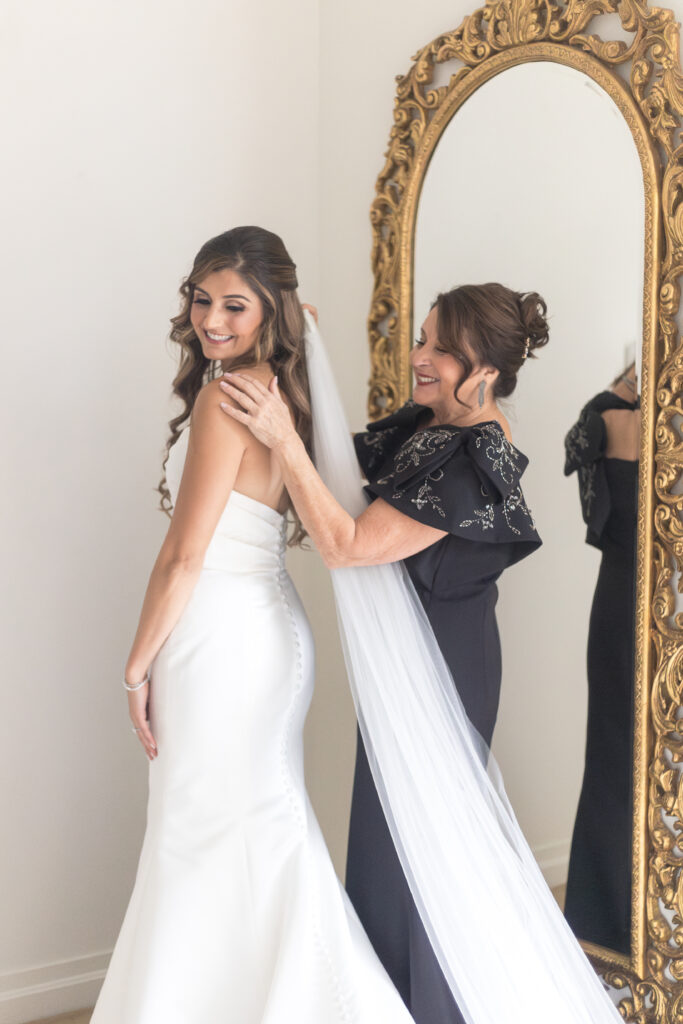 Bride and mother of bride putting wedding dress on