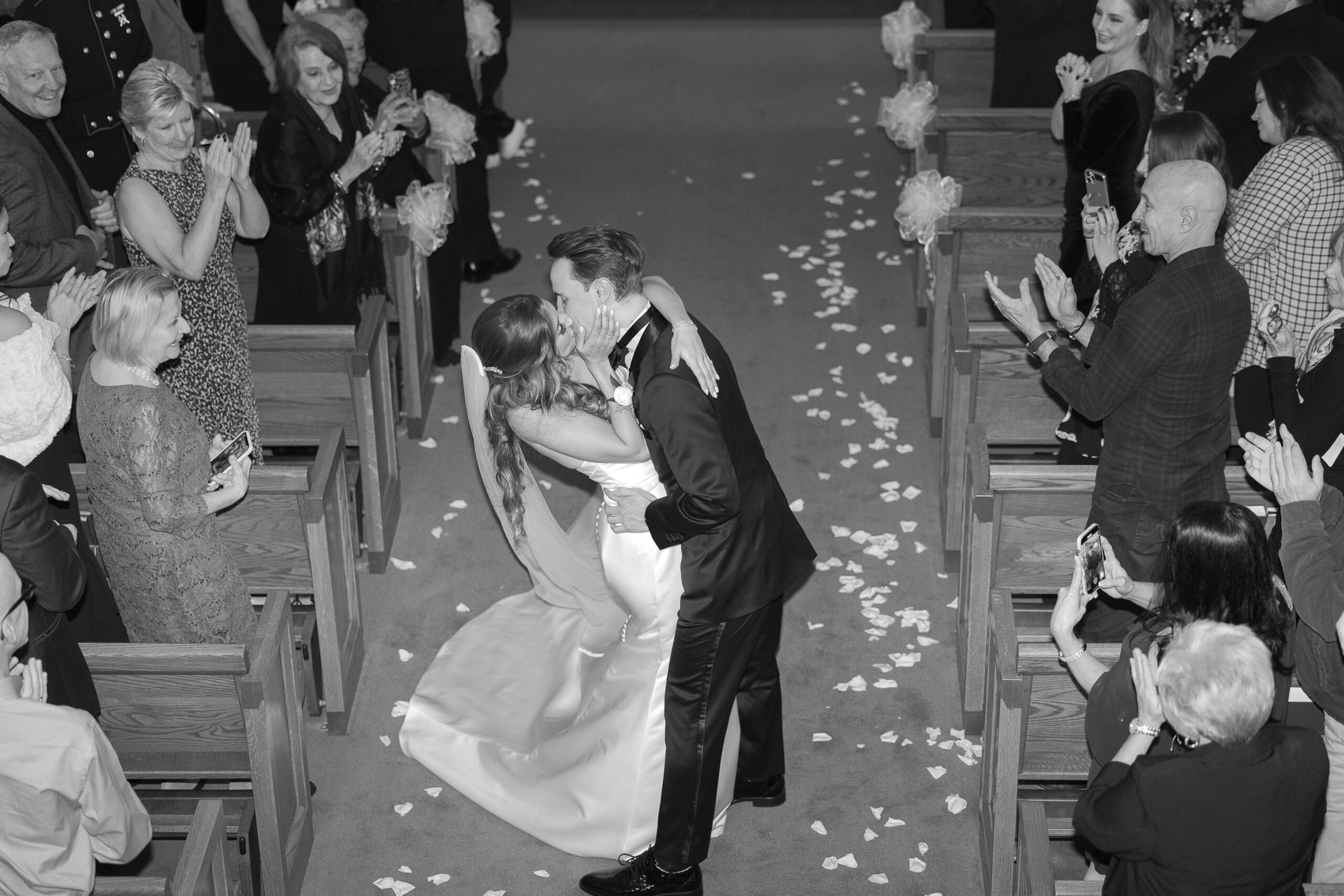 Black and white Greek bride and groom kiss at aisle