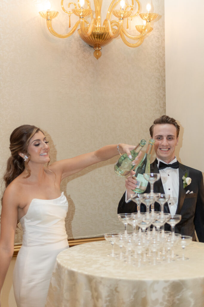 Bride and groom pouring on stacked glasses