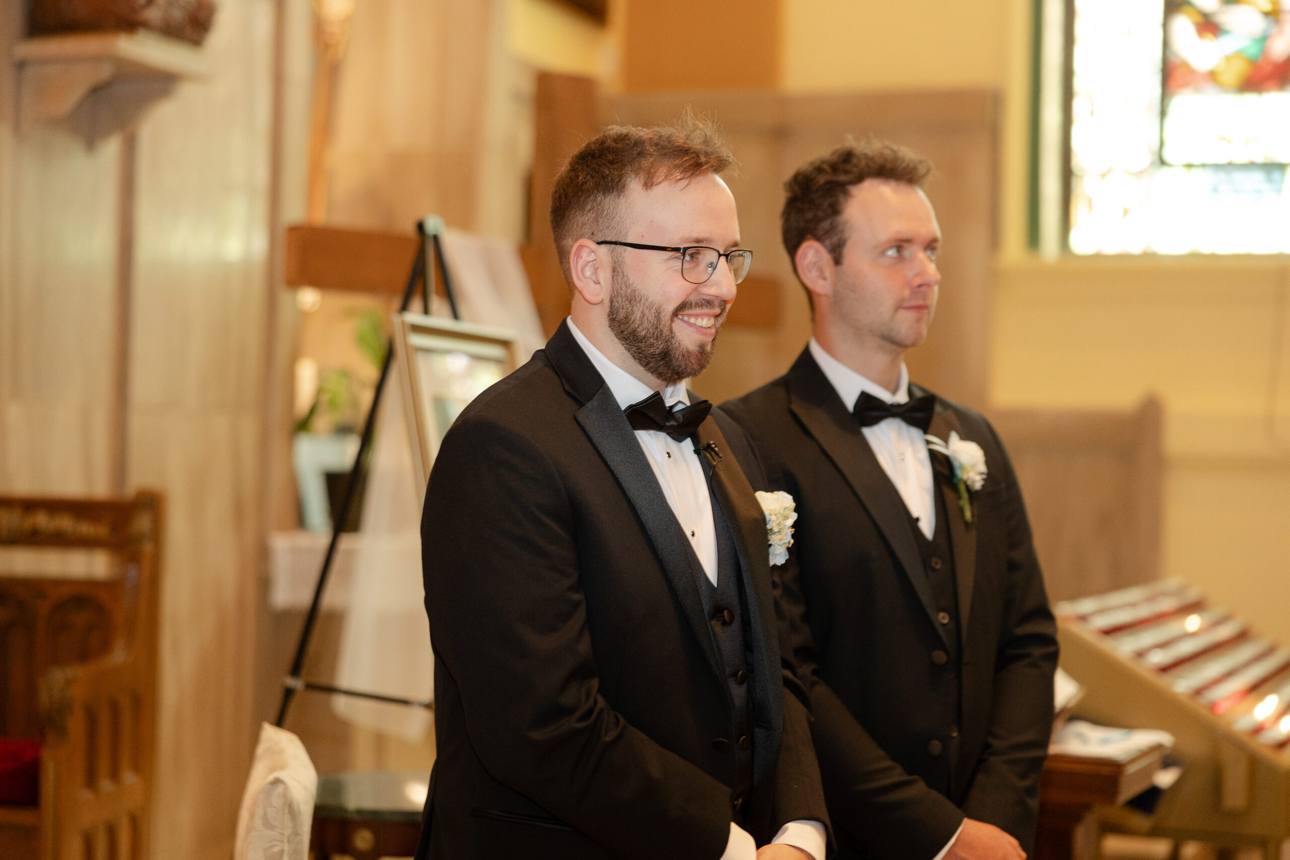 Groom reaction with bride walking down church aisle during Irish wedding ceremony
