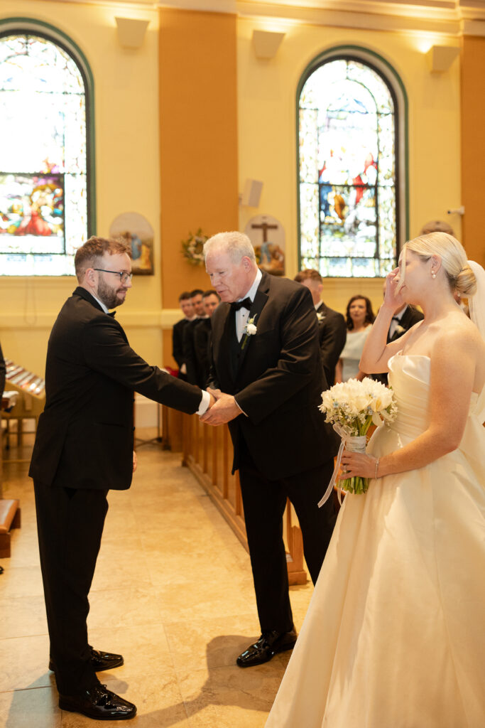 Groom reaction with bride walking down church aisle during Irish wedding ceremony