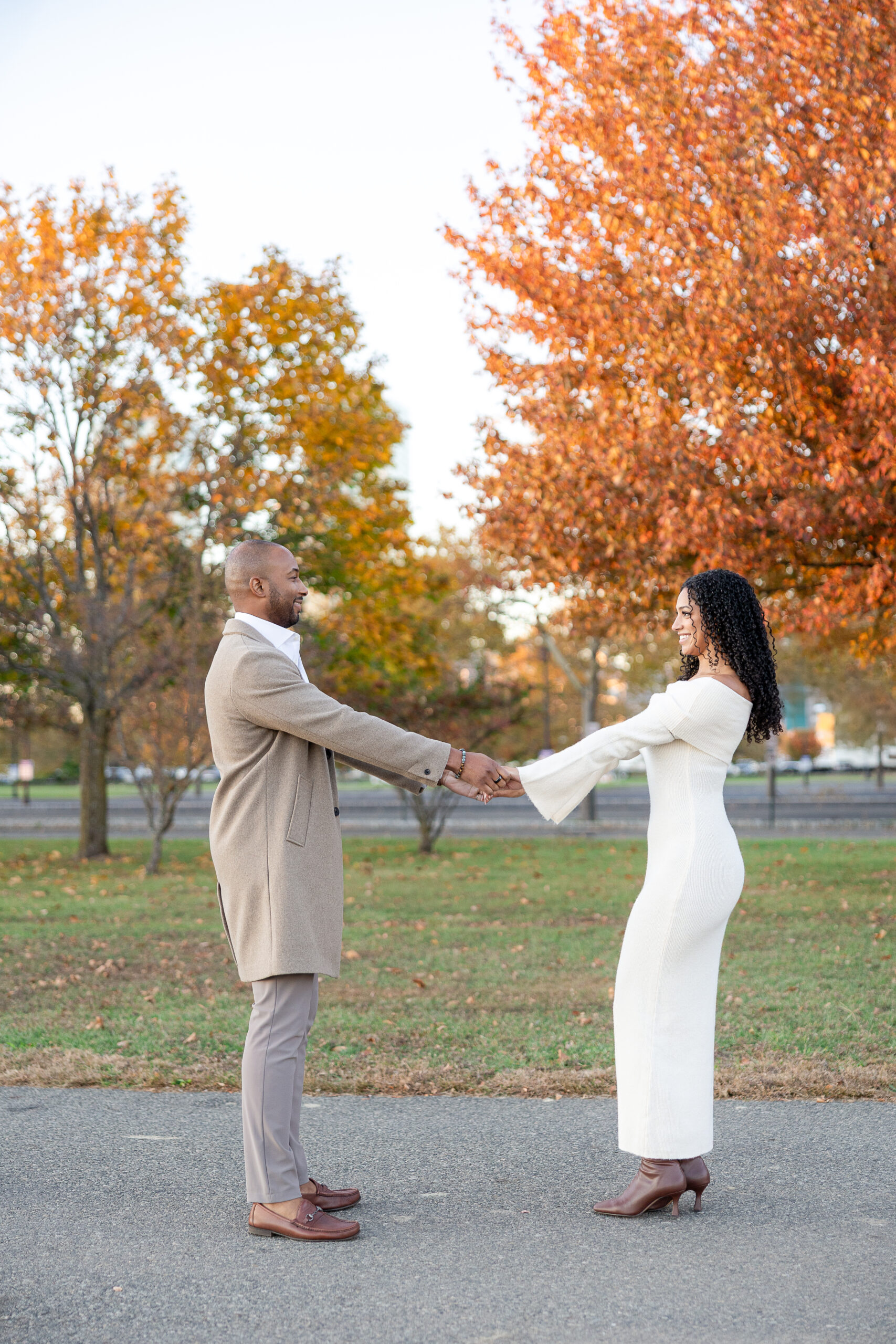 Couple walking hand in hand during engagement session at Liberty State Park in autumn