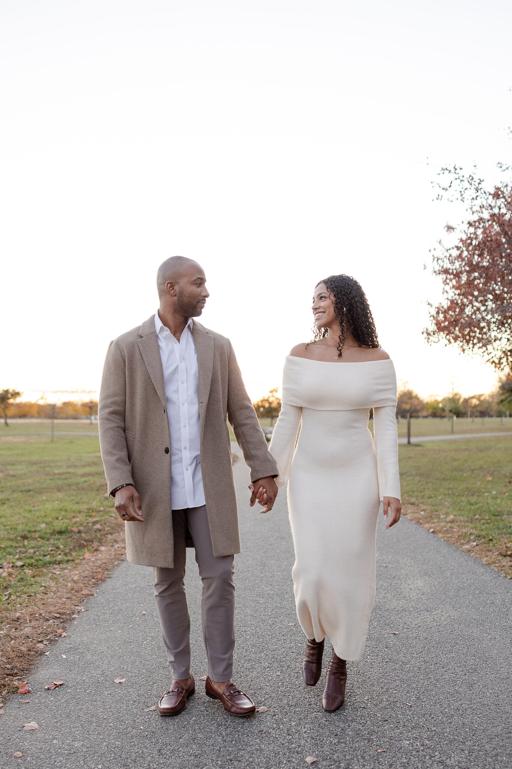 Couple walking hand in hand during engagement session at Liberty State Park in autumn