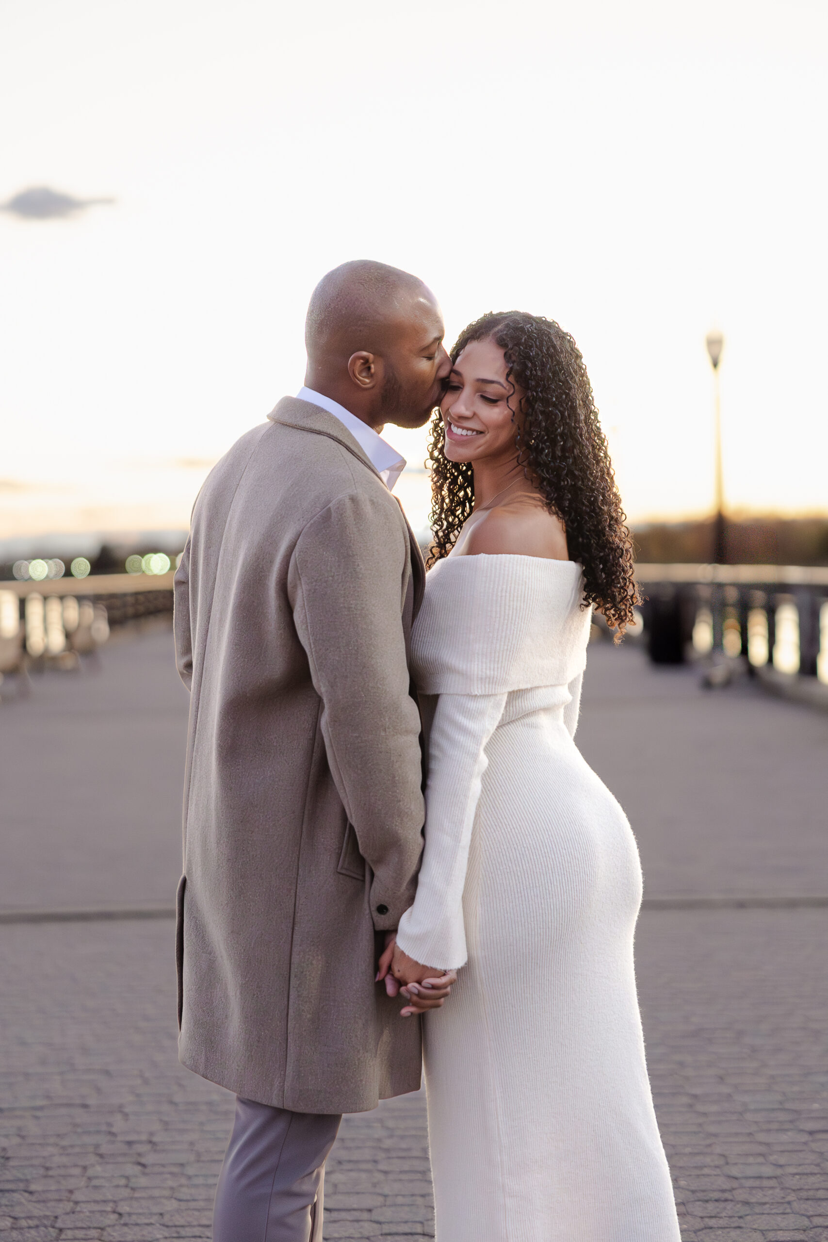 Candid engagement photo in Liberty State Park with NYC skyline at sunset