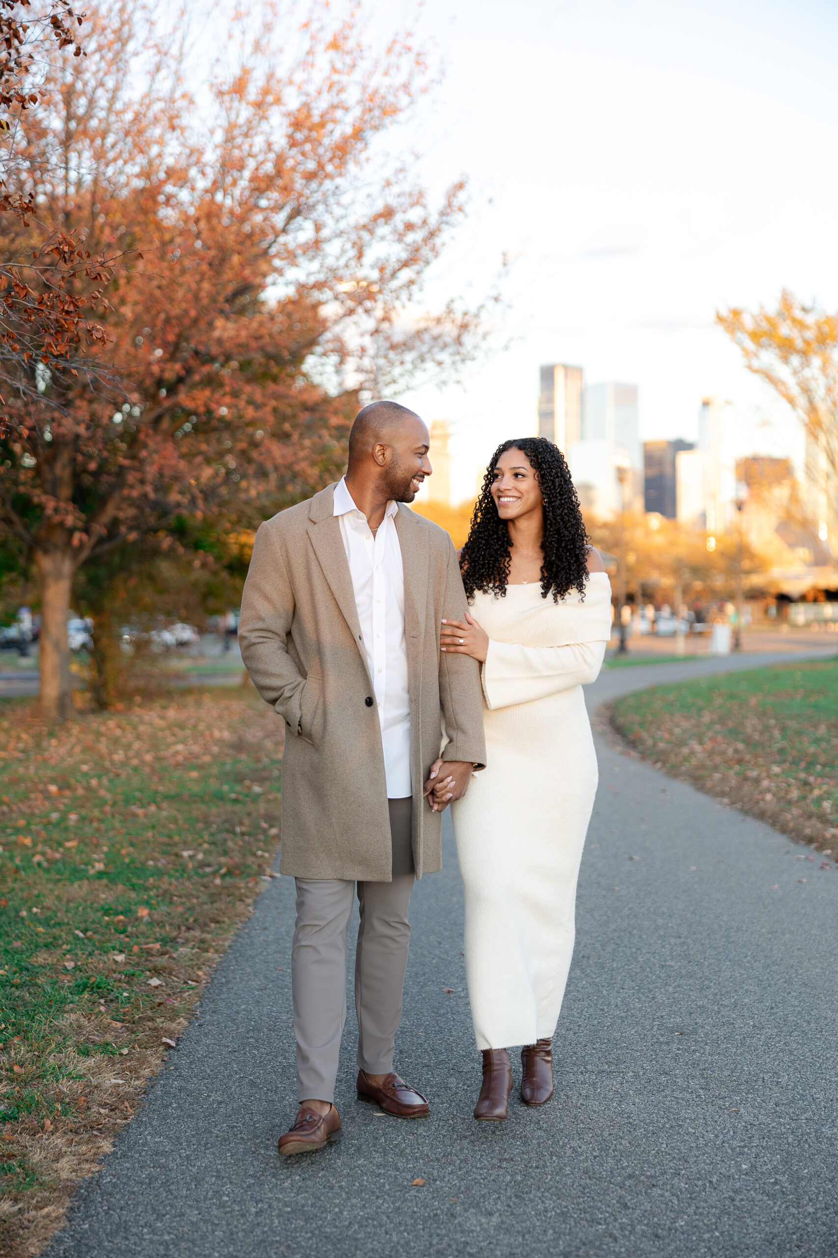 Couple walking hand in hand during engagement session at Liberty State Park in autumn