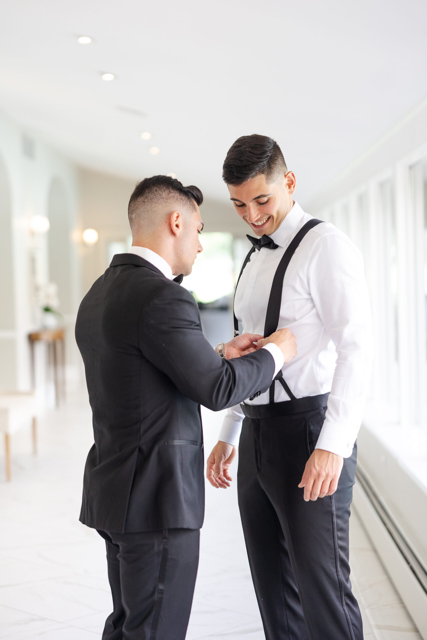 Groom getting dressed with his best man on wedding day